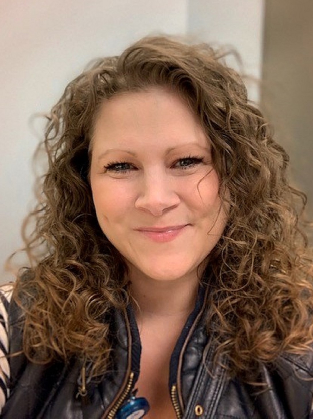 Woman with long, curly hair, smiling 