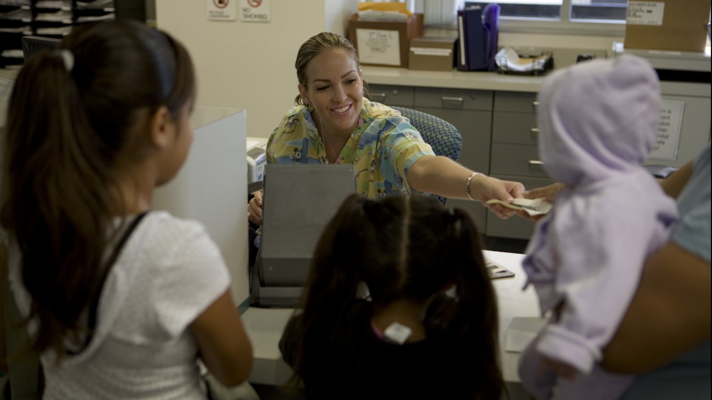 Receptionist welcoming three children to the clinic 