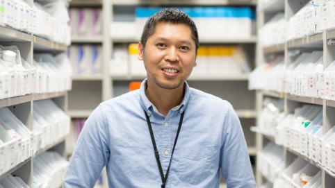 worker standing in a pharmacy stock room. 